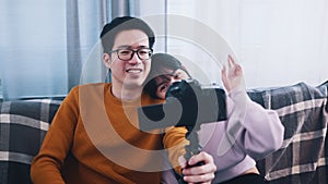 Young happy asian couple waving to the camera. Influencer streaming from the home