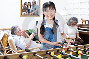 Young happy asian girl playing soccer table game together happiness. Grandmother and grandfather sit relax in living room in home