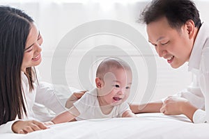 Young happy Asian mom dad and newborn baby playing at home