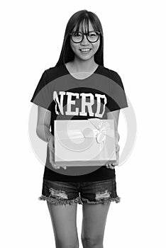 Young happy Asian nerd teenage girl smiling holding gift box