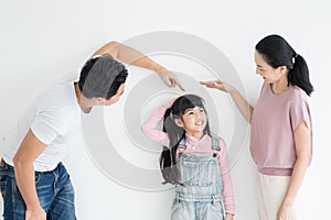 Young happy asian parents playing with their daughter on studio