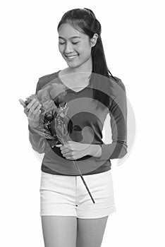 Young happy Asian teenage girl smiling holding red roses ready for Valentine`s day