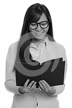 Young happy Asian teenage girl smiling and reading book