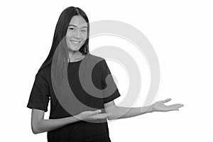 Young happy Asian teenage girl smiling and showing something