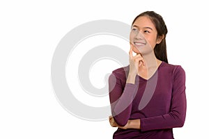 Young happy Asian teenage girl smiling and thinking