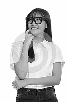 Young happy Asian teenage girl smiling and thinking