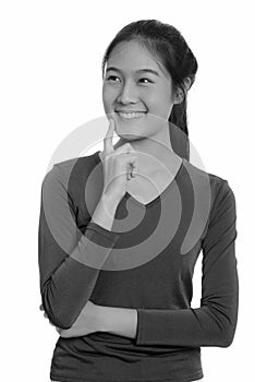 Young happy Asian teenage girl smiling and thinking