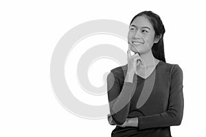 Young happy Asian teenage girl smiling and thinking