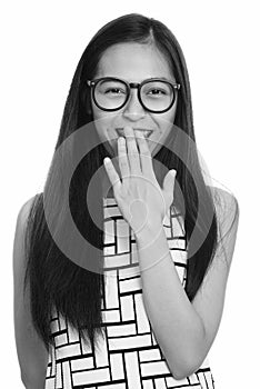 Young happy Asian teenage nerd girl smiling and laughing while covering mouth