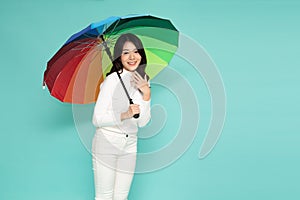 Young happy Asian woman holding colorful umbrella isolated on green background