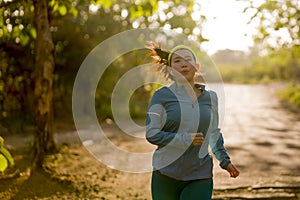 Young happy Asian woman running in wood on sunset . Attractive and healthy Korean girl doing jogging workout in beautiful