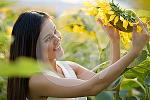 Young happy Asian woman smiling and looking at sunflower in the