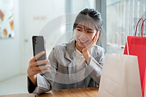 Young happy Asian woman is taking selfies on her phone while relaxing in a cafe in a shopping mall