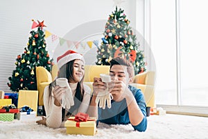 Young happy Asian woman wearing a Santa Claus hat surprised her boyfriend with gloves.