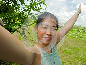 Young happy and attractive Asian Chinese woman taking selfie self portrait with mobile phone at tropical island posing cheerful