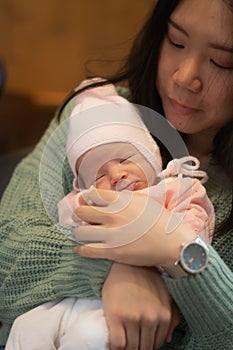 Young happy and attractive Asian Korean woman holding her adorable newborn baby girl in her arms sweet and tender in parenting and