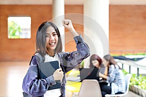 Young happy attractive asian student smiling to camera expression winner by raising hand and arm up to celebrate success on