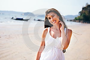 Young happy attractive and beautiful Caucasian adult woman smiling in white summer dress on tropical beach - waist up shot