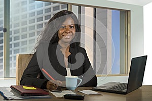 Young happy and attractive black African American businesswoman working confident at computer desk smiling satisfied in financial