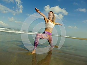 Young happy and attractive blond woman doing yoga and meditation exercise outdoors at beautiful beach in relax and flexibility