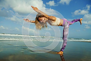 Young happy and attractive blond woman doing yoga and meditation exercise outdoors at beautiful beach in relax and flexibility