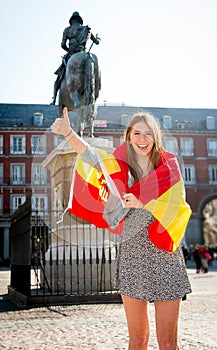 Young happy attractive exchange student girl having fun in town visiting Madrid city showing Spain flag