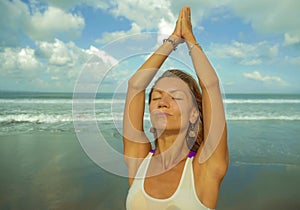 Young happy and attractive fit and skinny blond woman doing yoga and relaxation exercise outdoors at beautiful beach in relax and