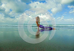 Young happy and attractive fit and skinny blond woman doing yoga and relaxation exercise outdoors at beautiful beach in relax and