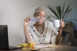 Young happy and attractive hipster black afro American woman drinking tea or coffee at home office working cheerful with laptop co