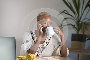 Young happy and attractive hipster black afro American woman drinking tea or coffee at home office working cheerful with laptop co