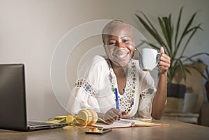 Young happy and attractive hipster black afro American woman drinking tea or coffee at home office working cheerful with laptop co