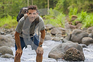 Young happy and attractive man with travel backpack hiking in river at forest feeling free enjoying nature and fresh environment