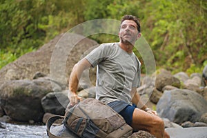 Young happy and attractive man with travel backpack hiking in river at forest feeling free enjoying nature and fresh environment