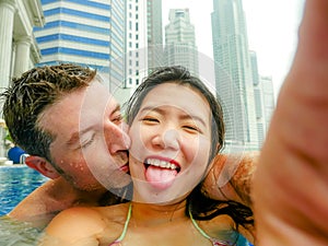 Young happy and attractive playful couple taking selfie picture together with mobile phone at luxury urban hotel kissing at infini photo