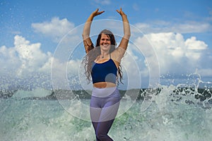 Young happy and attractive red hair woman playing excited spreading arms feeling free and relaxed getting wet by sea waves