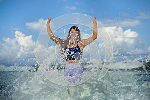 Young happy and attractive red hair woman playing excited spreading arms feeling free and relaxed getting wet by sea waves