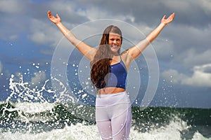 Young happy and attractive red hair woman playing excited spreading arms feeling free and relaxed getting wet by sea waves