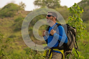 Young happy and attractive sporty hiker man with trekking backpack hiking at mountain feeling free enjoying travel getaway