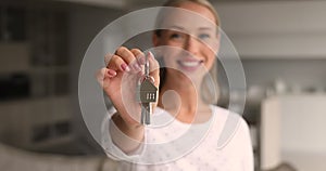 Young happy attractive woman showing keys to camera.
