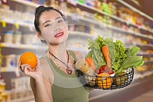 Young happy and beautiful Asian Chinese woman holding basket full of fresh vegetables and fruits smiling cheerful buying healthy