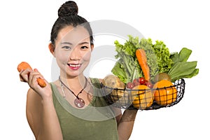 Young happy and beautiful Asian Chinese woman holding basket full of vegetables smiling cheerful holding carrot playful in healthy