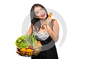 Young happy and beautiful Asian Chinese woman holding basket full of vegetables smiling cheerful holding carrot playful in healthy