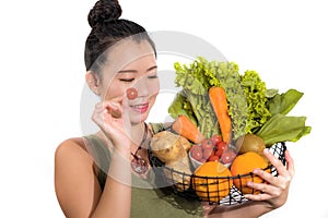 Young happy and beautiful Asian Chinese woman holding basket full of vegetables smiling cheerful holding carrot playful in healthy