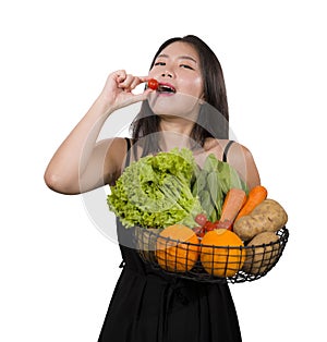 Young happy and beautiful Asian Chinese woman holding basket full of vegetables smiling cheerful playful in healthy organic and