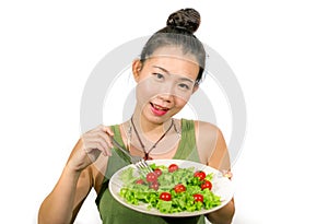 Young happy and beautiful Asian Chinese woman holding dish with green lettuce and tomato salad smiling cheerful in diet and weight