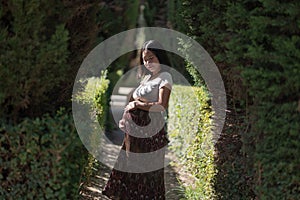 Young happy and beautiful Asian Chinese woman posing outdoors happy and cheerful at city park pregnant showing her belly proud