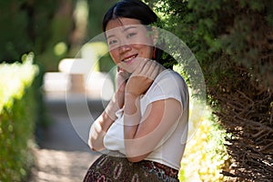 Young happy and beautiful Asian Chinese woman posing outdoors happy and cheerful at city park pregnant showing her belly proud