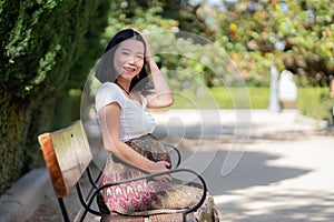 Young happy and beautiful Asian Chinese woman pregnant showing her belly proud and cheerful smiling at city park bench happy in
