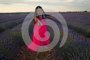 Young happy and beautiful Asian Chinese woman in Summer dress enjoying nature free and playful outdoors at purple lavender flowers