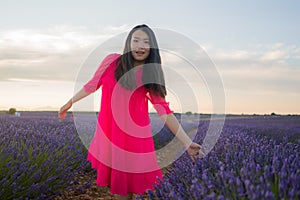 Young happy and beautiful Asian Chinese woman in Summer dress enjoying nature free and playful outdoors at purple lavender flowers